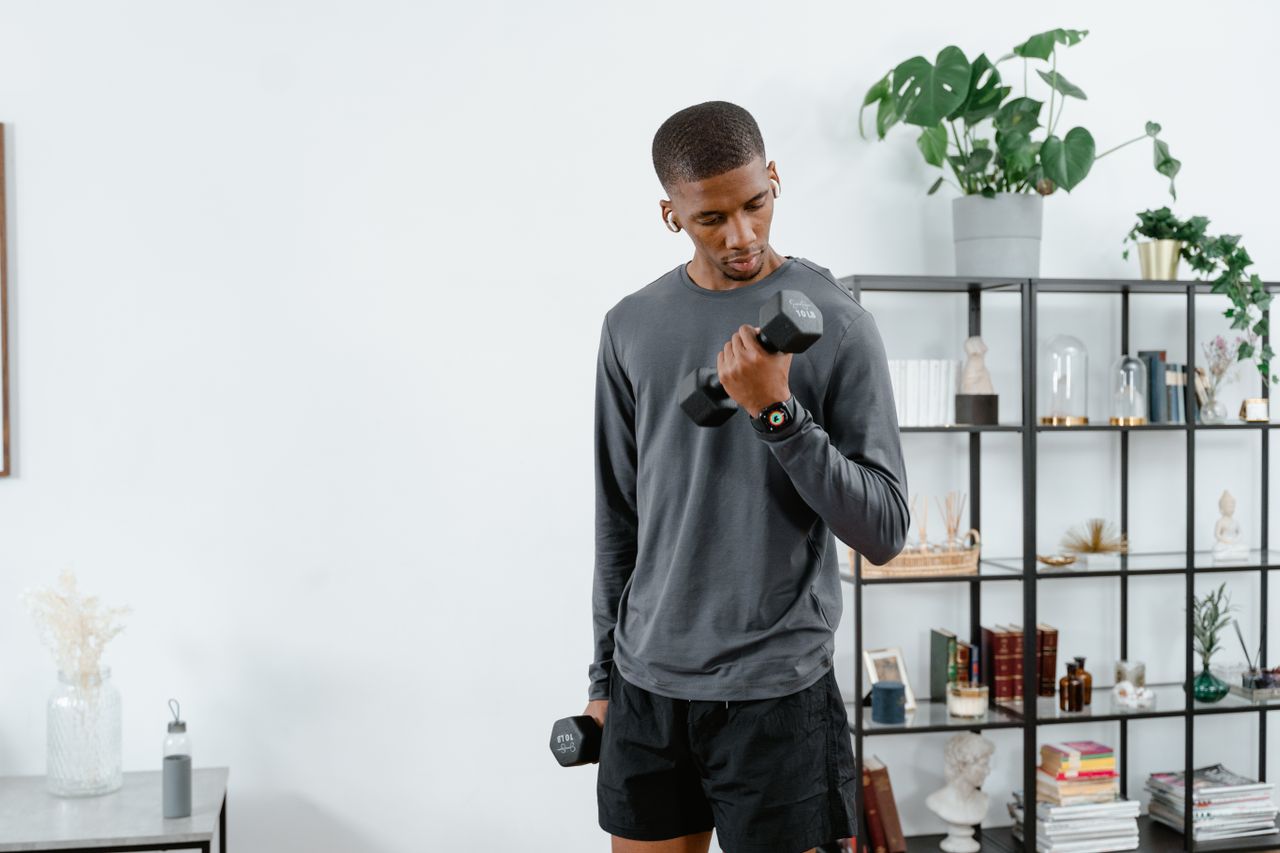 Young man exercising with dumbbells indoors for a healthy lifestyle.